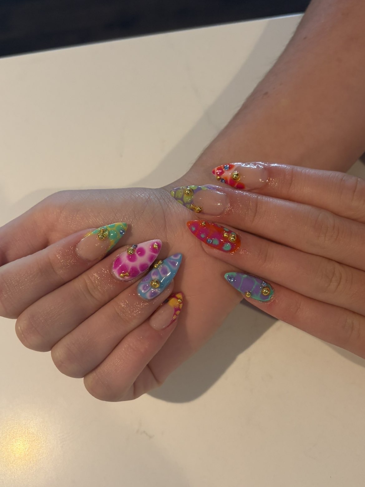 Rainbow tie-dye nails with gold gems